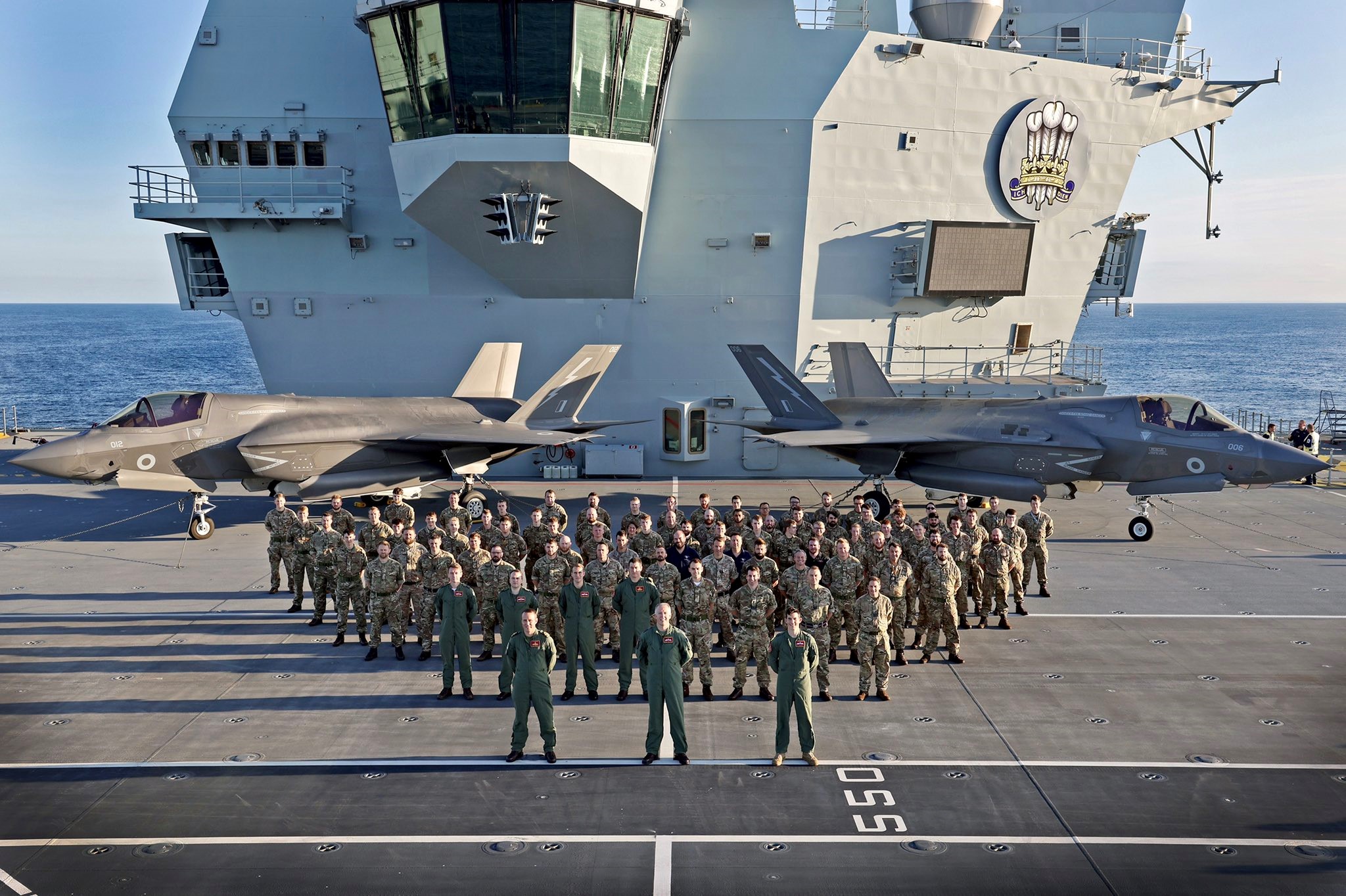 Personnel stand on flight deck of Aircraft carrier.